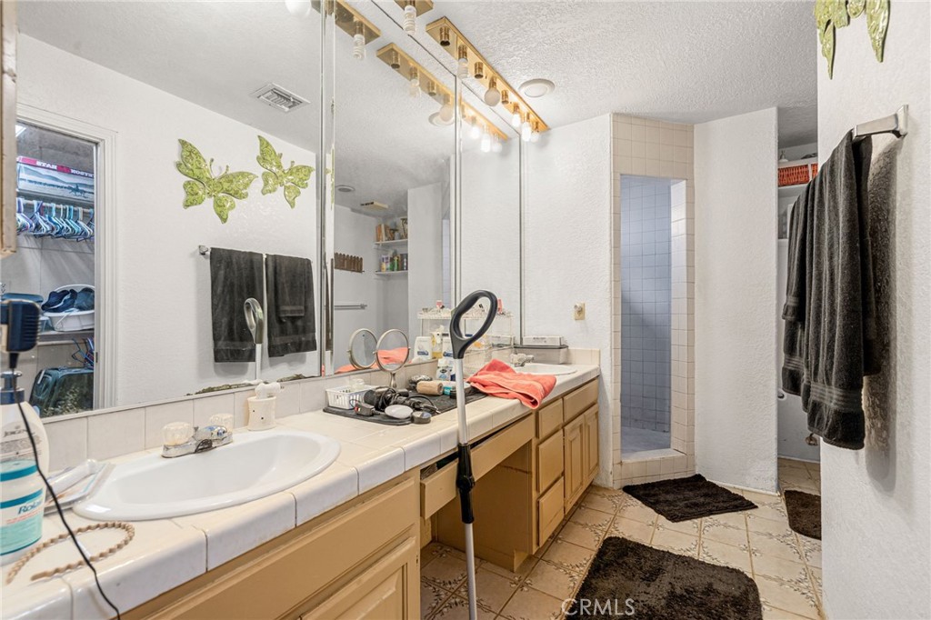 Bathroom with a long mirrored vanity and tiled walk-in shower.