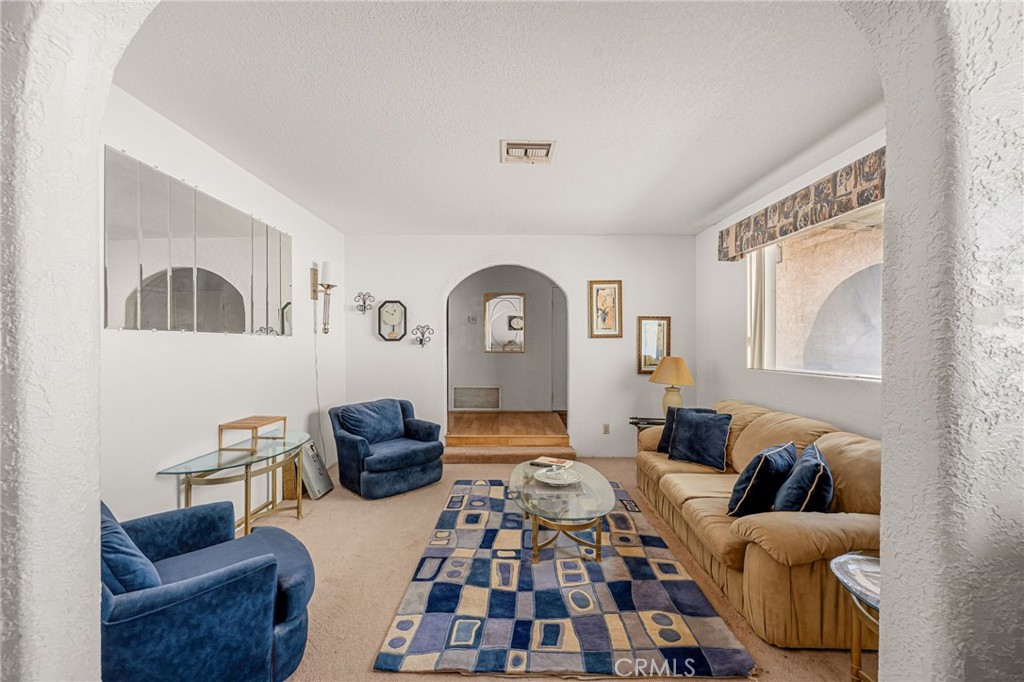 Living room with a tan sofa, blue armchairs, and a geometric patterned rug.