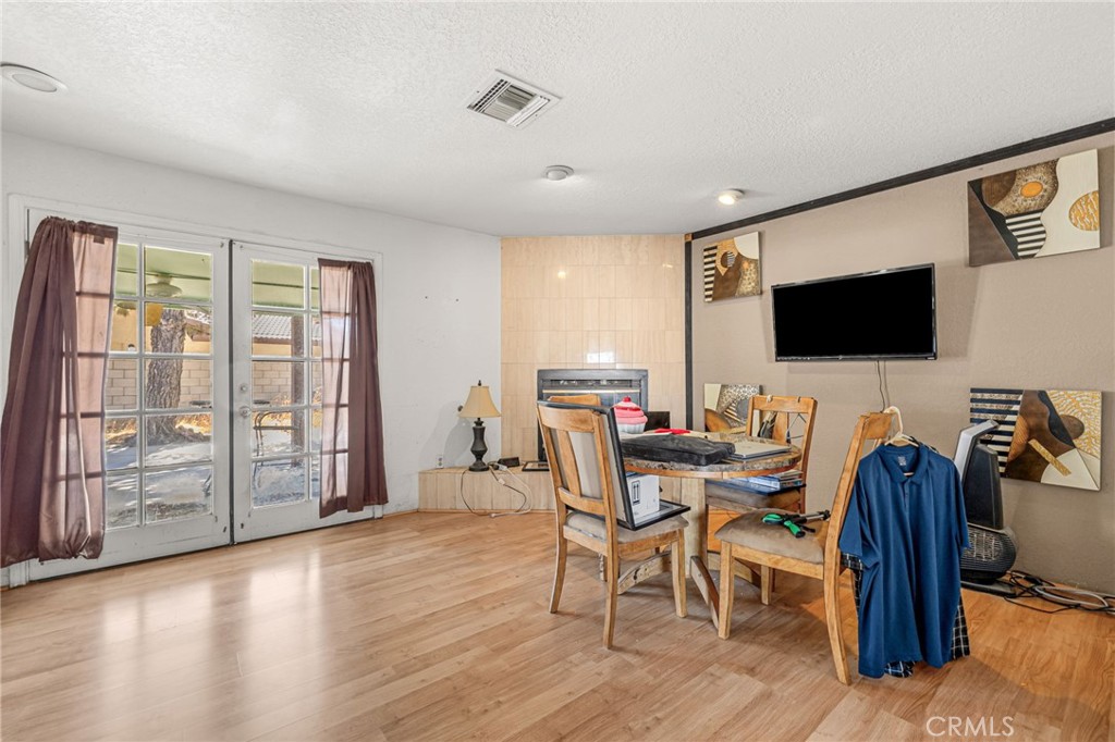 Living and dining area with a tiled fireplace and glass French doors.