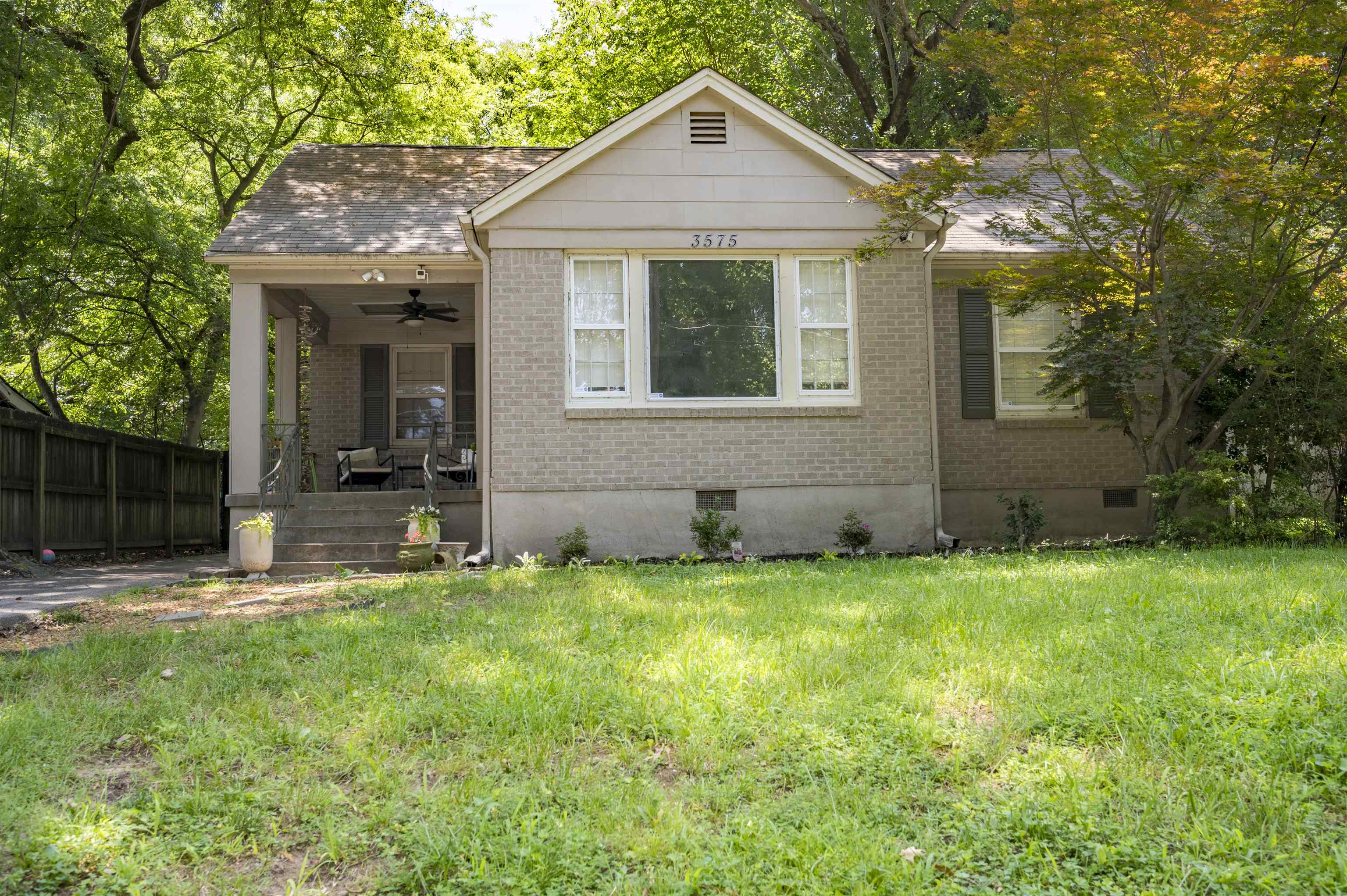 Brick house with a covered porch and mature trees; house number 3575 above the front window.