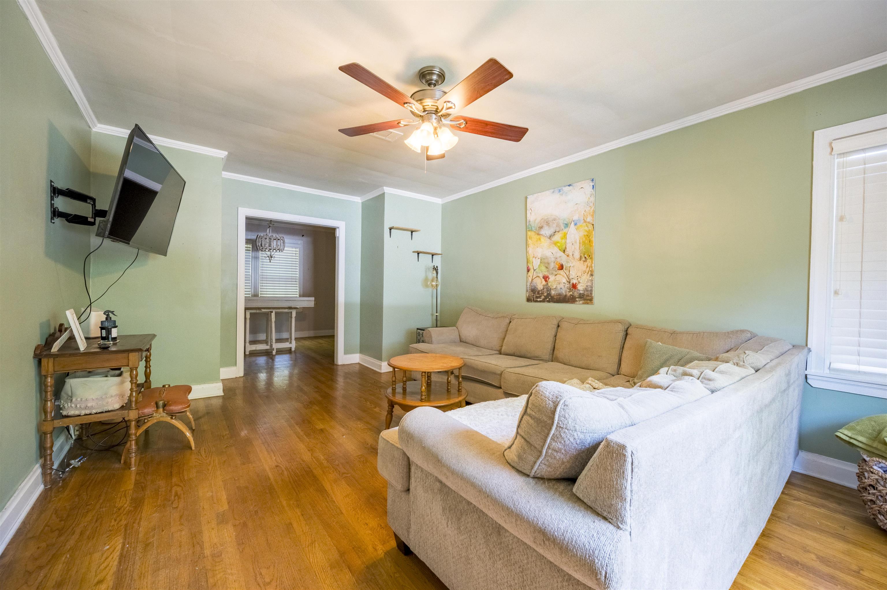 Living room with a beige sectional, hardwood floors, and pale green walls.
