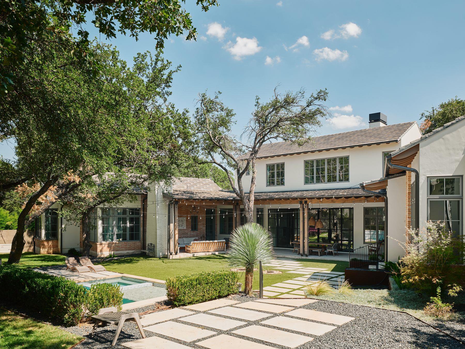 Rear exterior of a two-story home with covered patio, small pool, and stone courtyard.