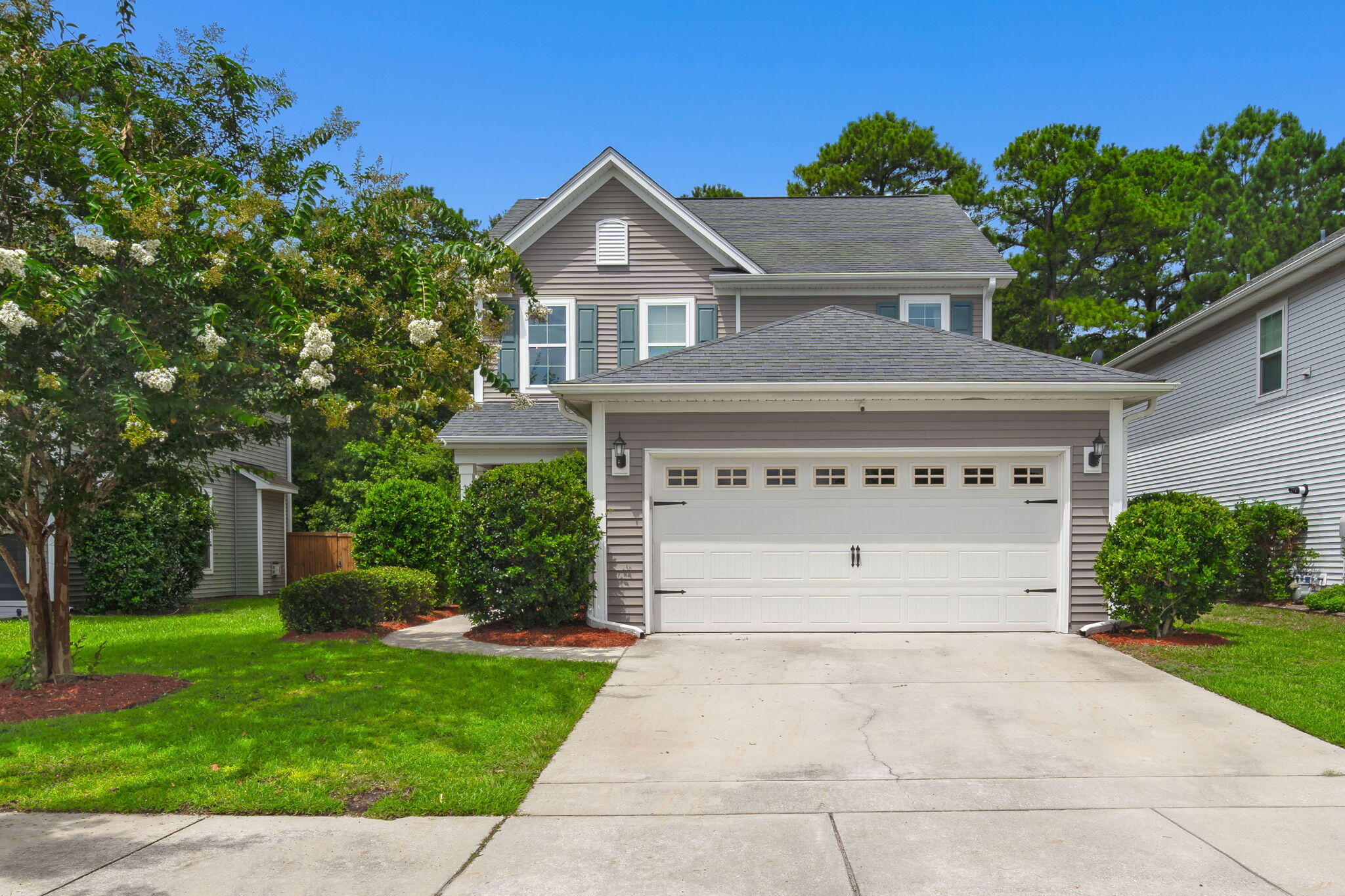 Gray two-story house with a large white garage, broad driveway, and landscaped front yard.
