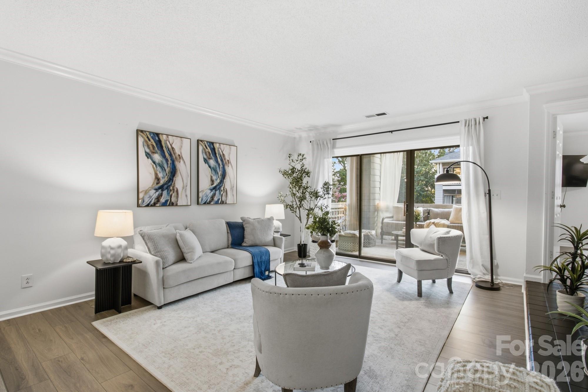 Furnished living room with a gray sofa, blue accent throw, and sliding glass doors to a balcony.