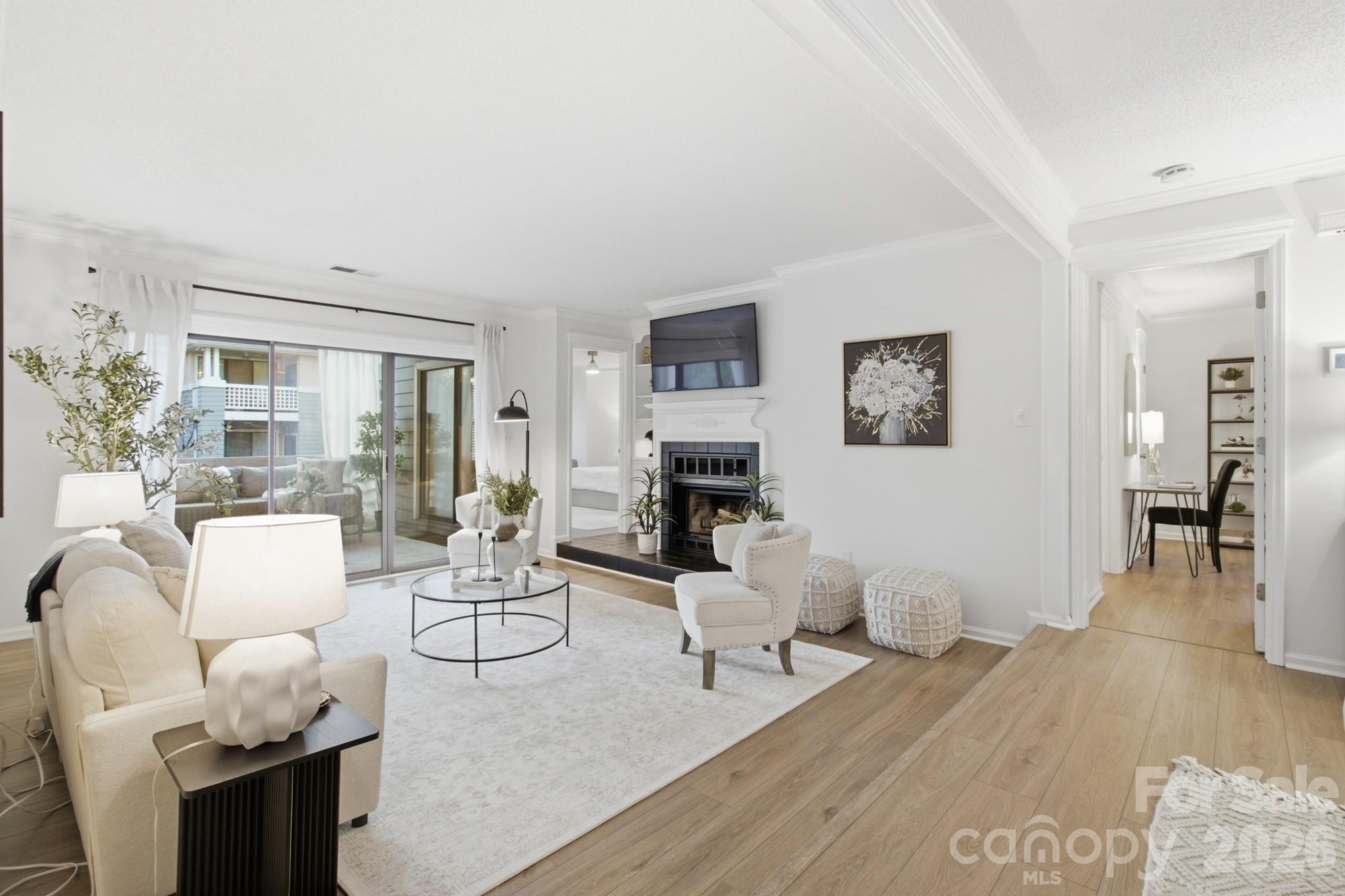 Furnished living room with a fireplace, wall-mounted television, and sliding glass doors to a balcony.