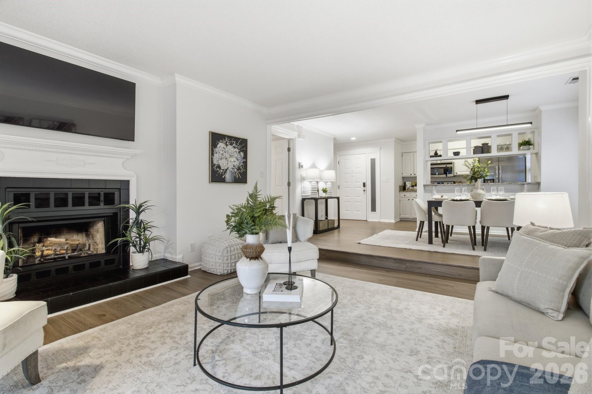 Living room with black-tiled fireplace, neutral seating, and an open dining area and kitchen.