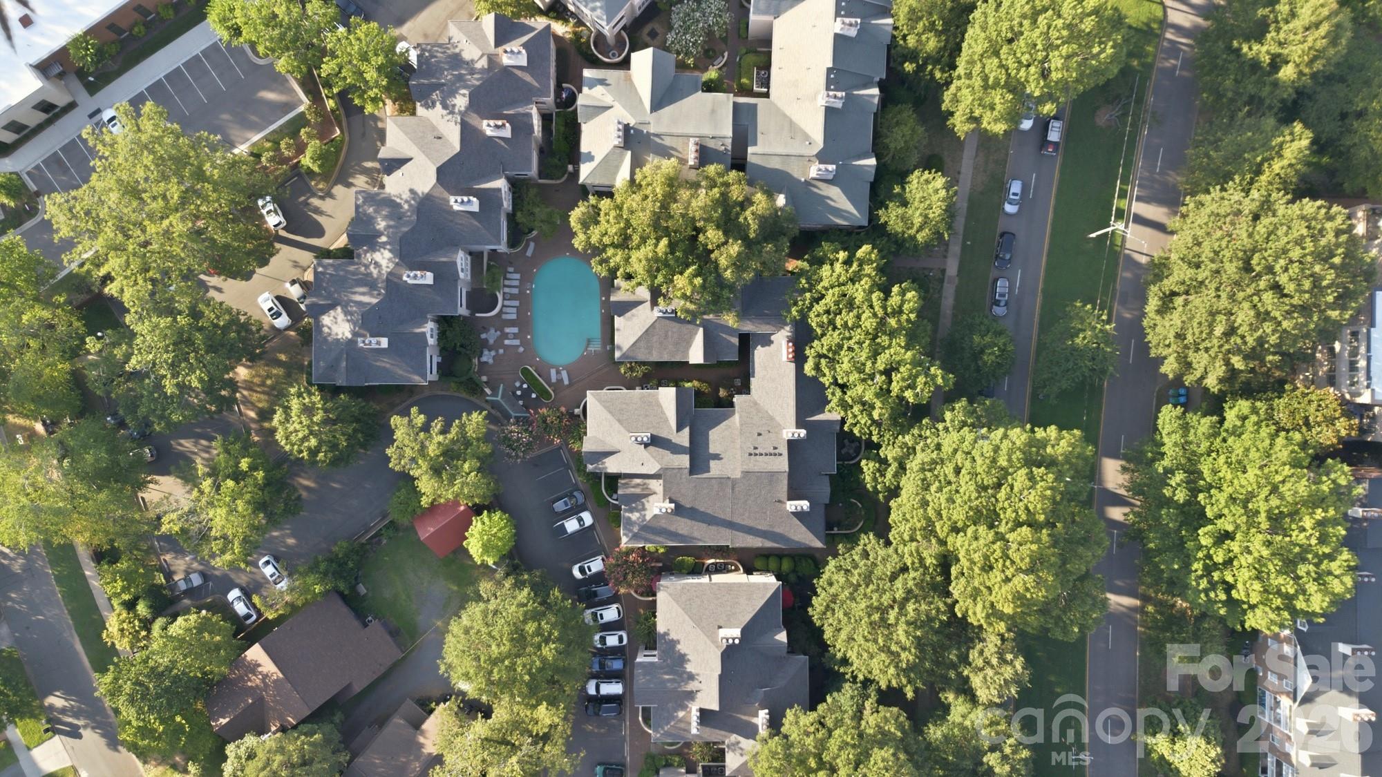 Aerial view of a residential complex with a central swimming pool and tree-lined grounds.
