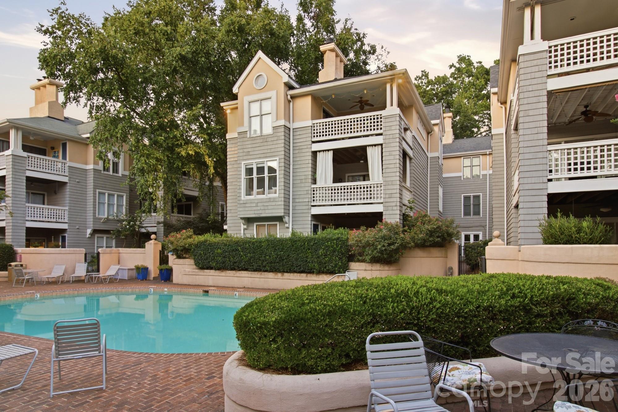 Condominium building with balconies overlooking a landscaped courtyard pool.