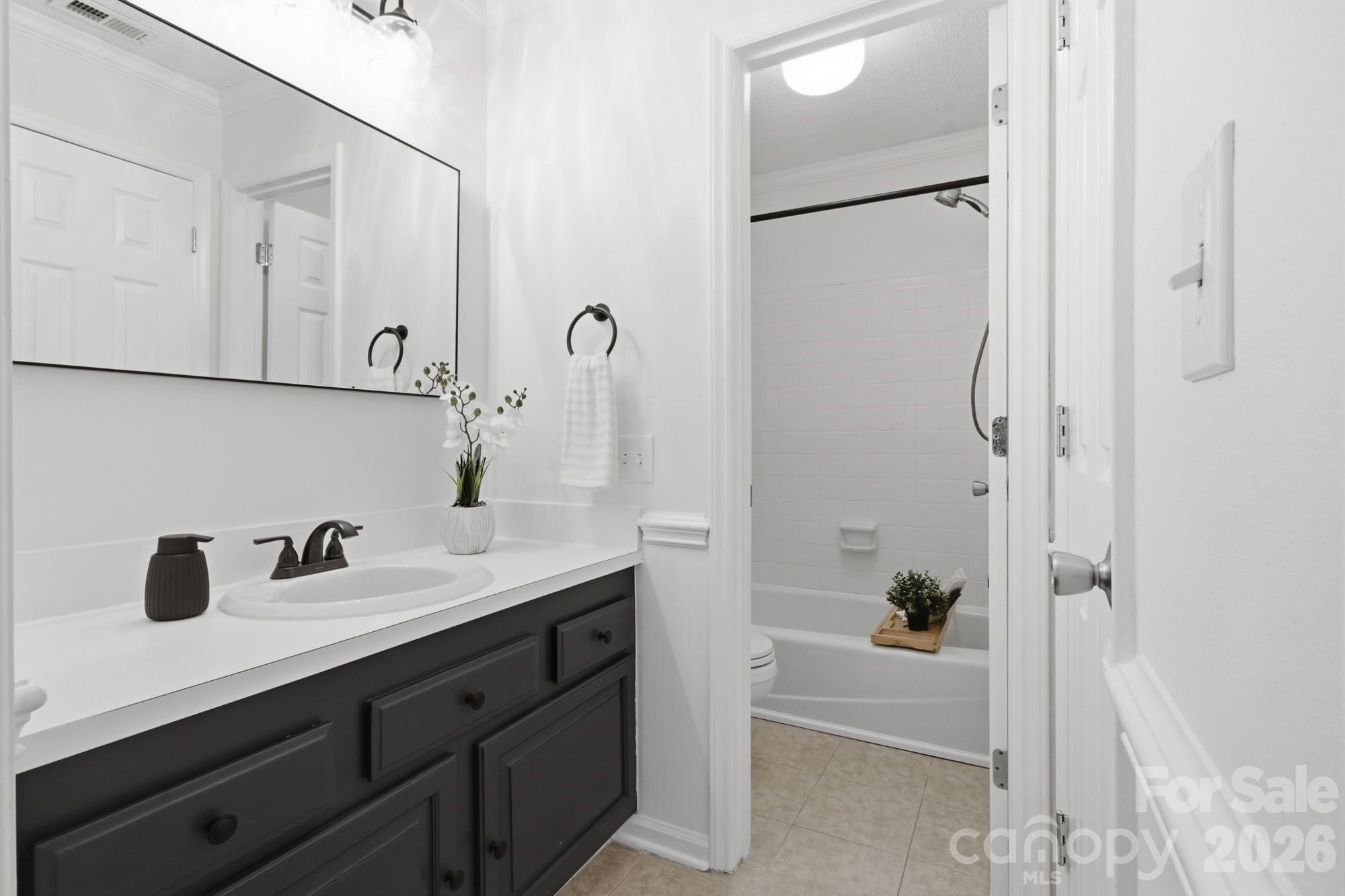 Bathroom with a dark gray vanity and a white-tiled tub-shower.