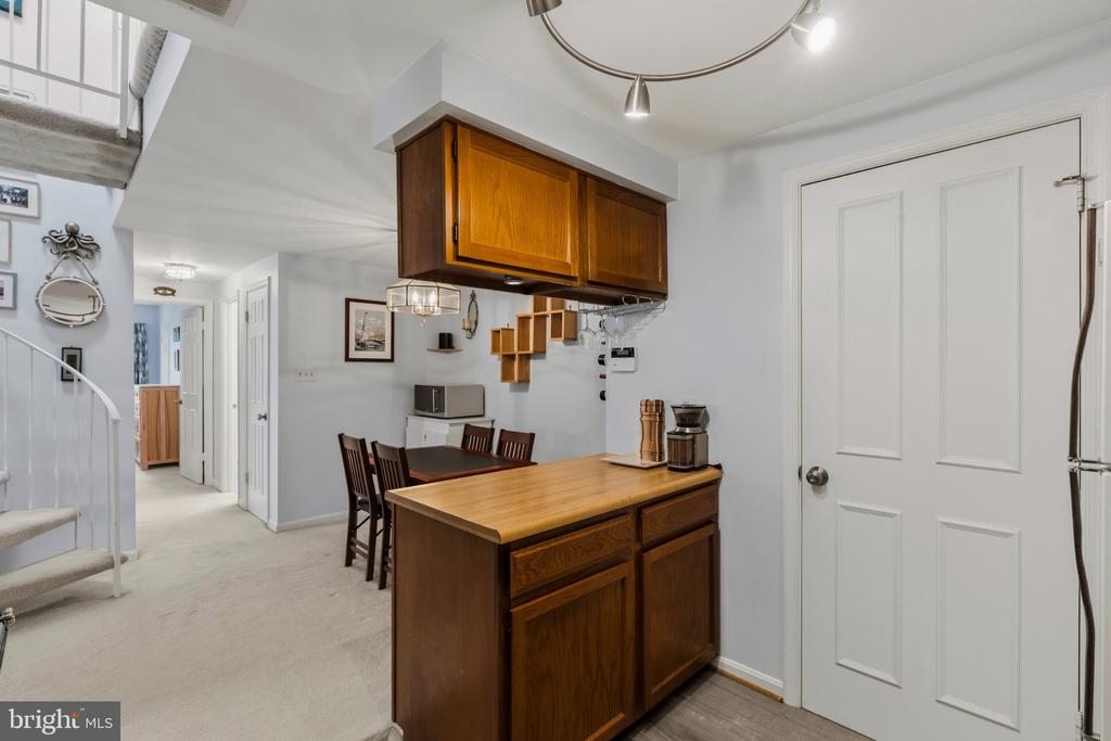 Compact kitchen with a wood island and overhead cabinets beside a small dining area.