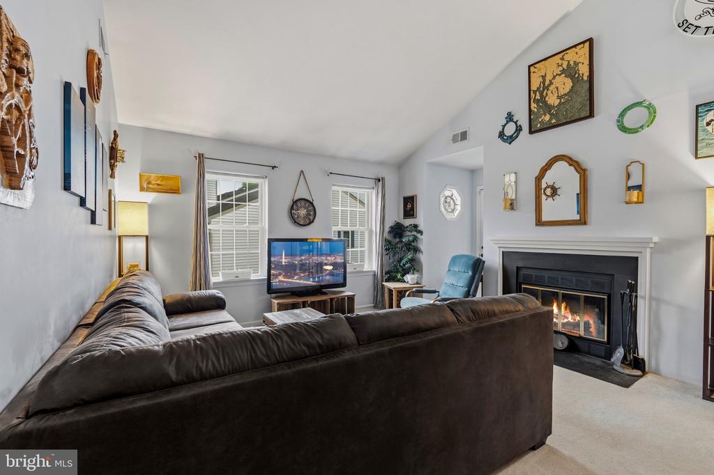 Living room with a dark sectional sofa, vaulted ceiling, and fireplace.