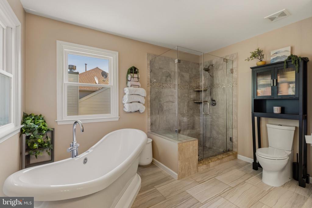Bathroom with a freestanding soaking tub and glass-enclosed tiled shower.