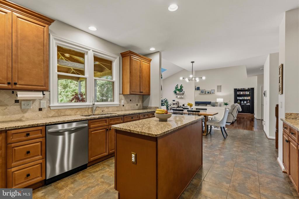 Kitchen with a granite island, warm wood cabinets, and an open dining and living area.