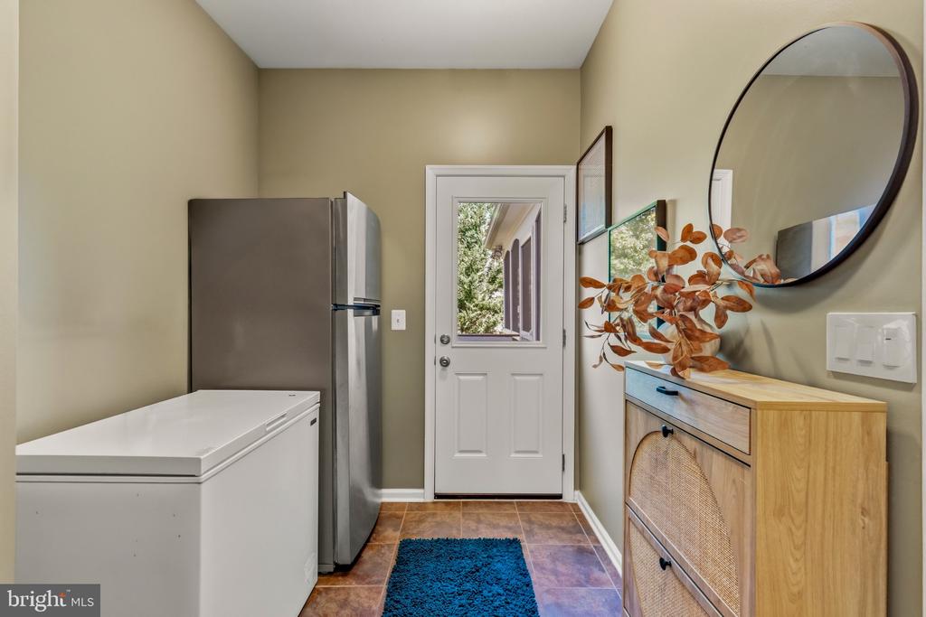 Laundry room with a chest freezer, refrigerator, and exterior door.