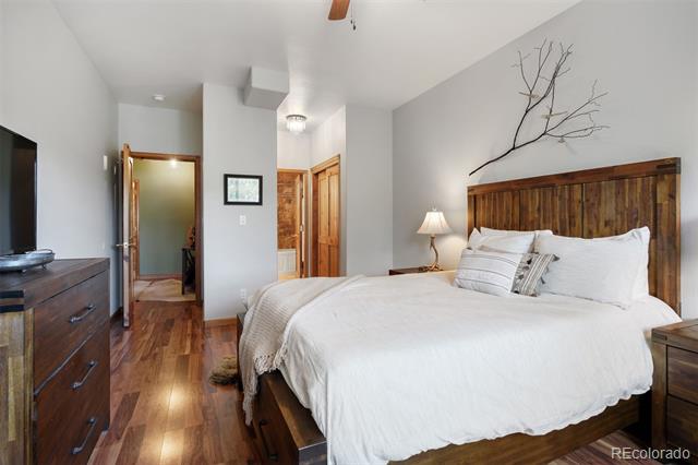 Bedroom with white bedding, a rustic wood headboard, and hardwood floors