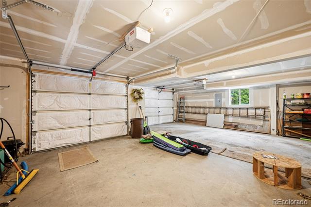 Spacious unfinished garage with two overhead doors, storage shelves, and recreational equipment on the concrete floor.