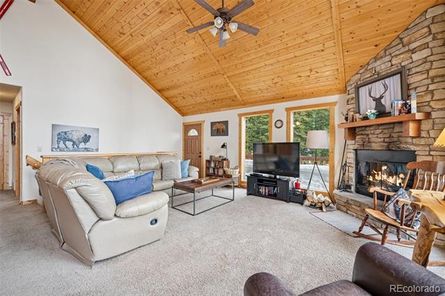 Living room with a vaulted wood ceiling, stone fireplace, and sectional sofa.