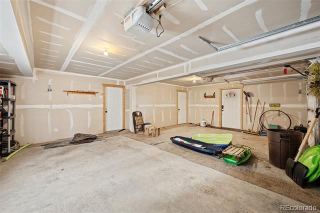 Unfinished garage with kayaks and storage bins on the concrete floor.