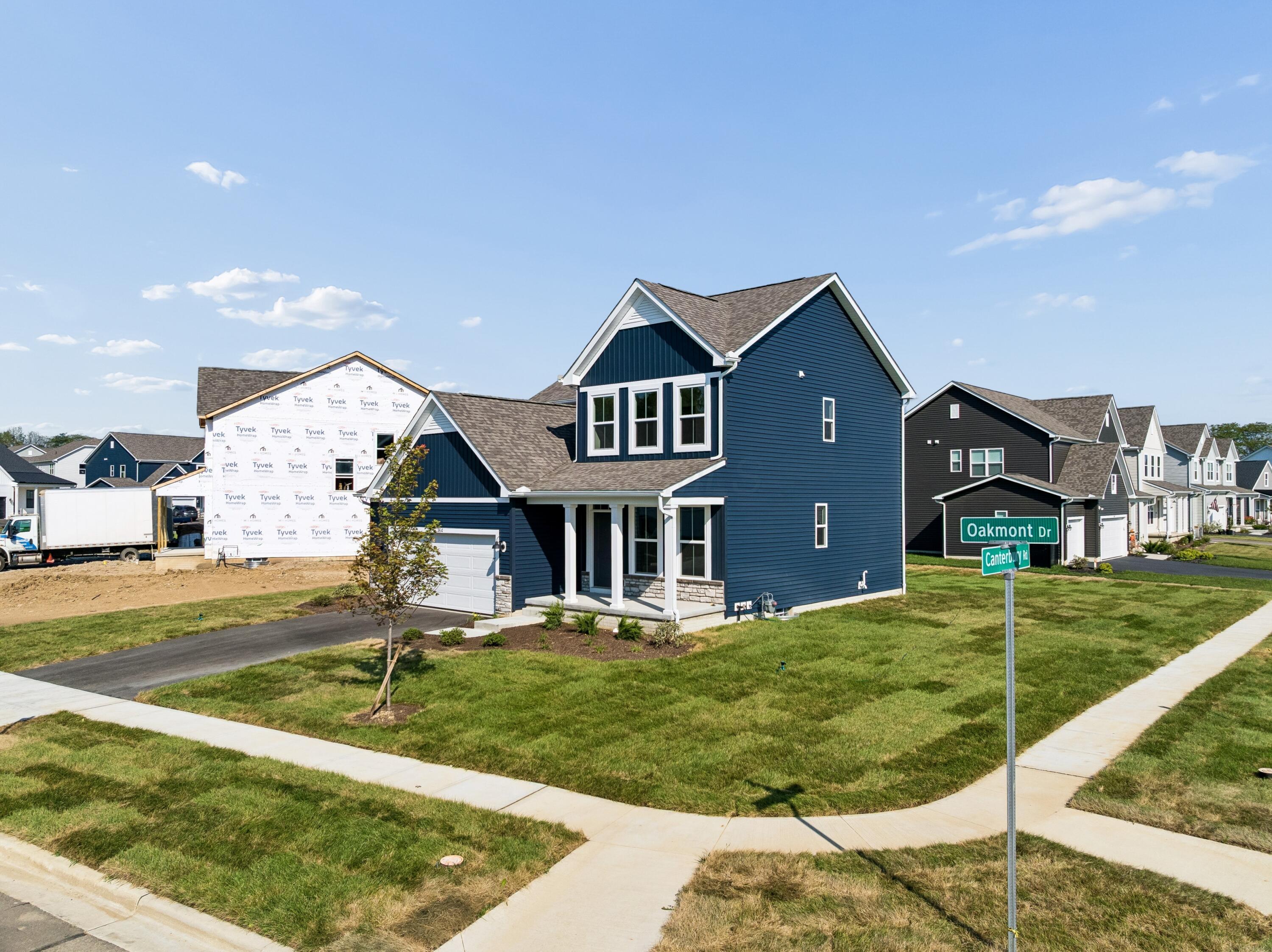 Navy-blue two-story house with white trim, front porch, and attached garage on Oakmont Drive.