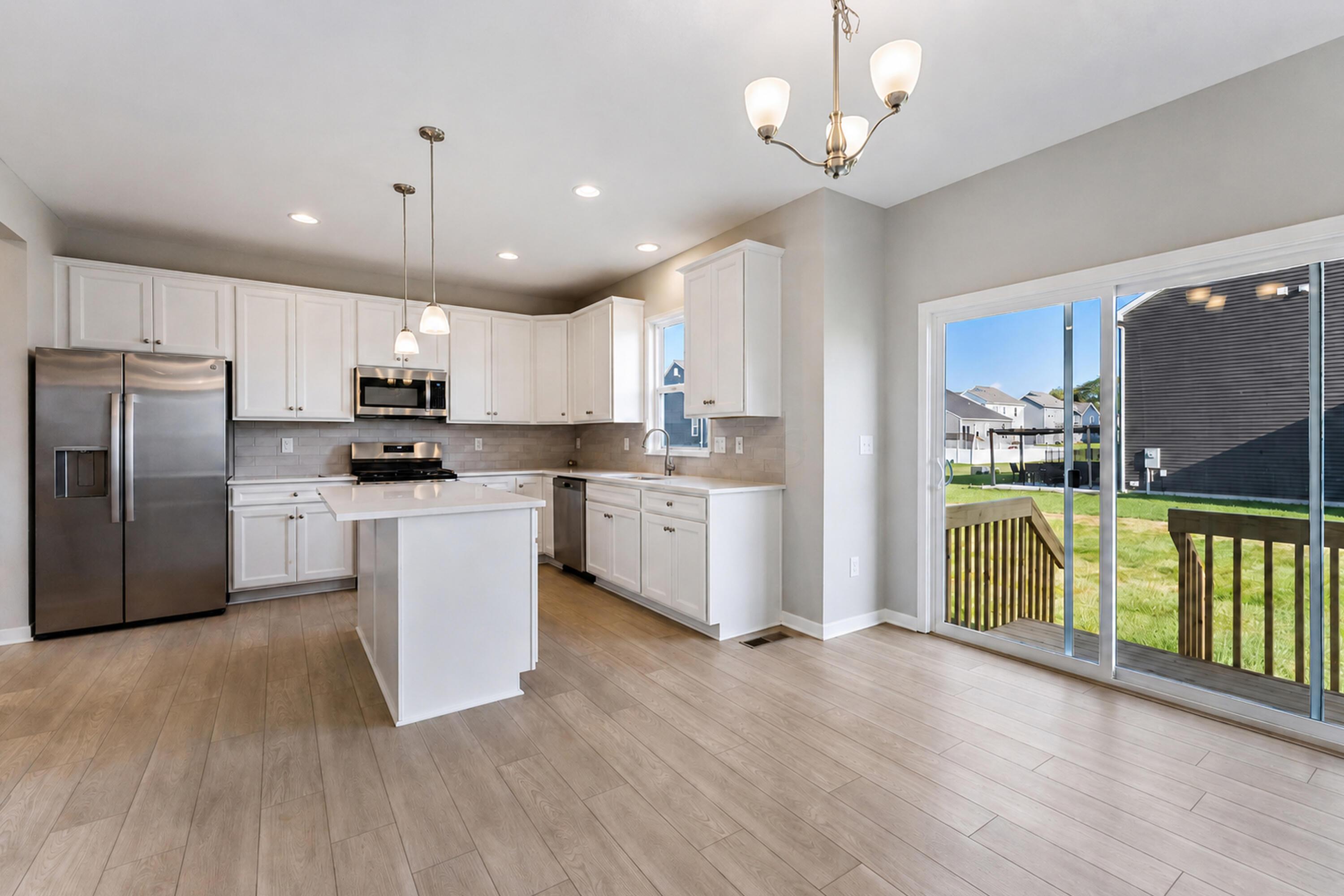 Kitchen with white cabinetry, stainless appliances, a central island, and sliding doors to a deck.