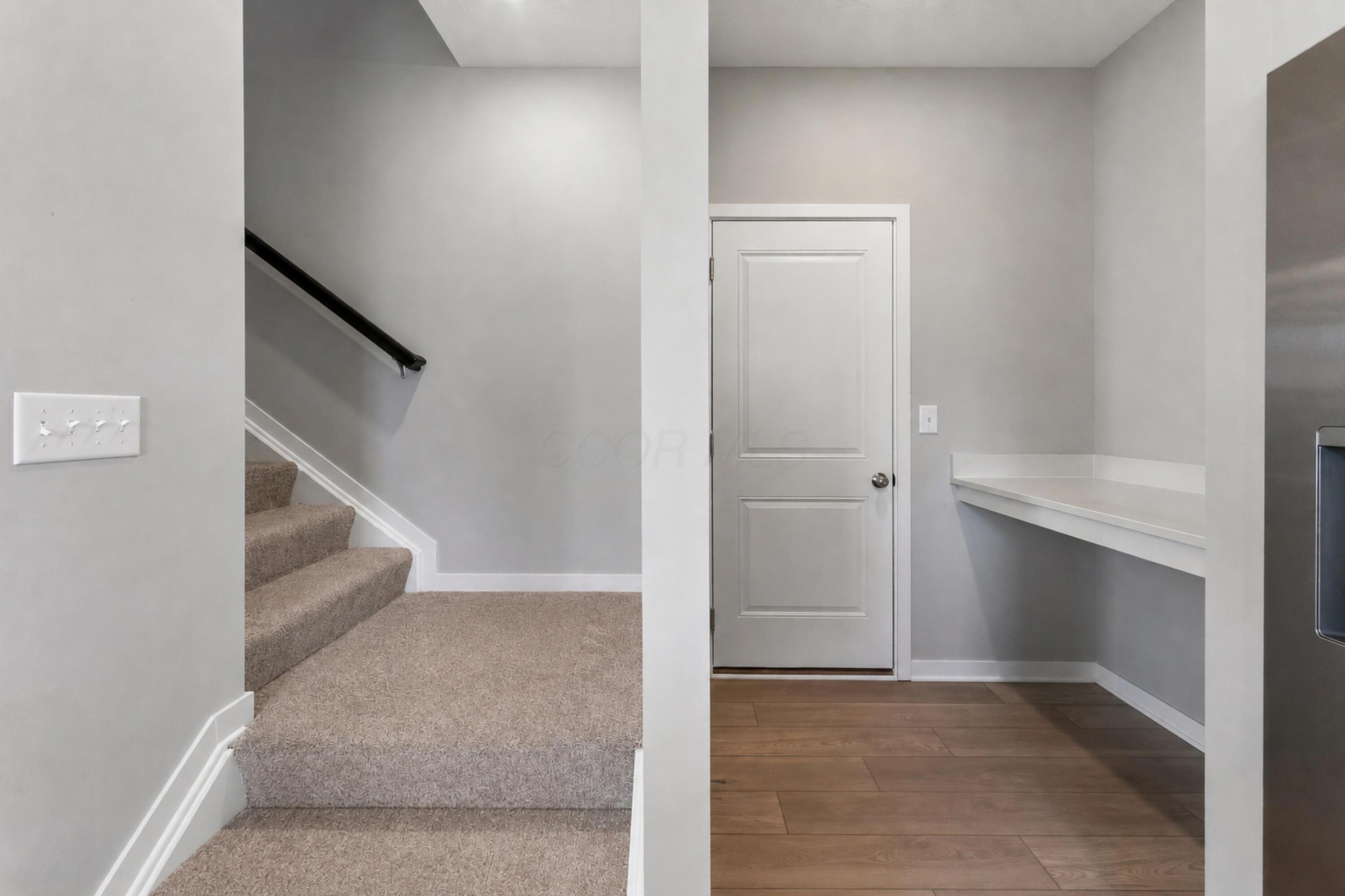 Entryway with carpeted stairs, a white paneled door, and a built-in counter.