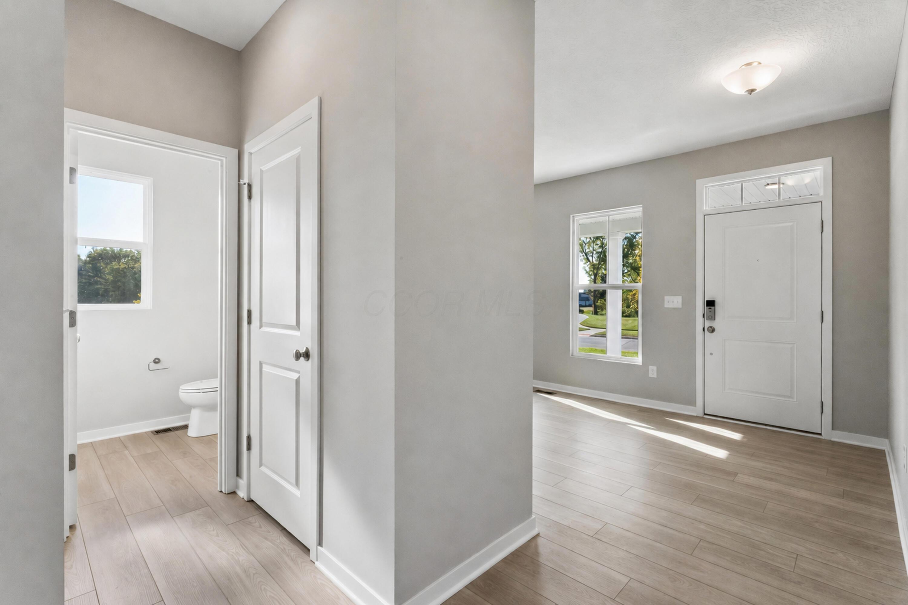 Entryway with a white front door and an open doorway to a bathroom.