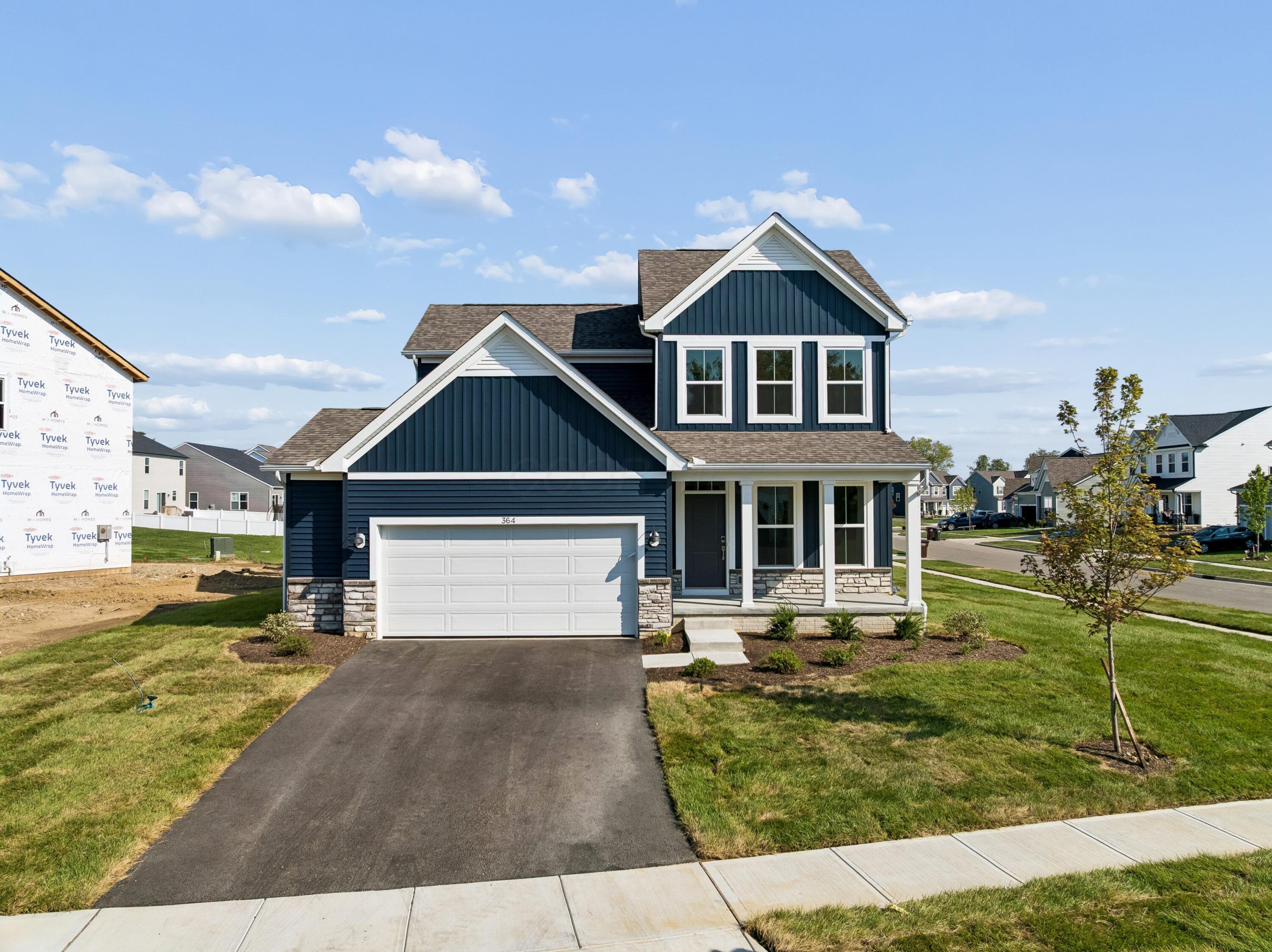 Navy-blue two-story home with white trim, stone accents, and a two-car garage.