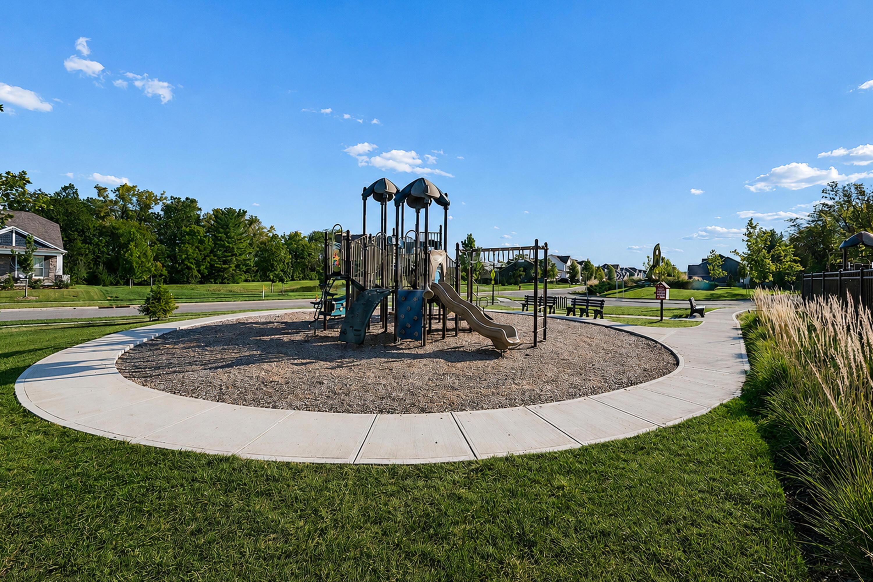Neighborhood playground with a large play structure, slides, and a curved concrete walkway.