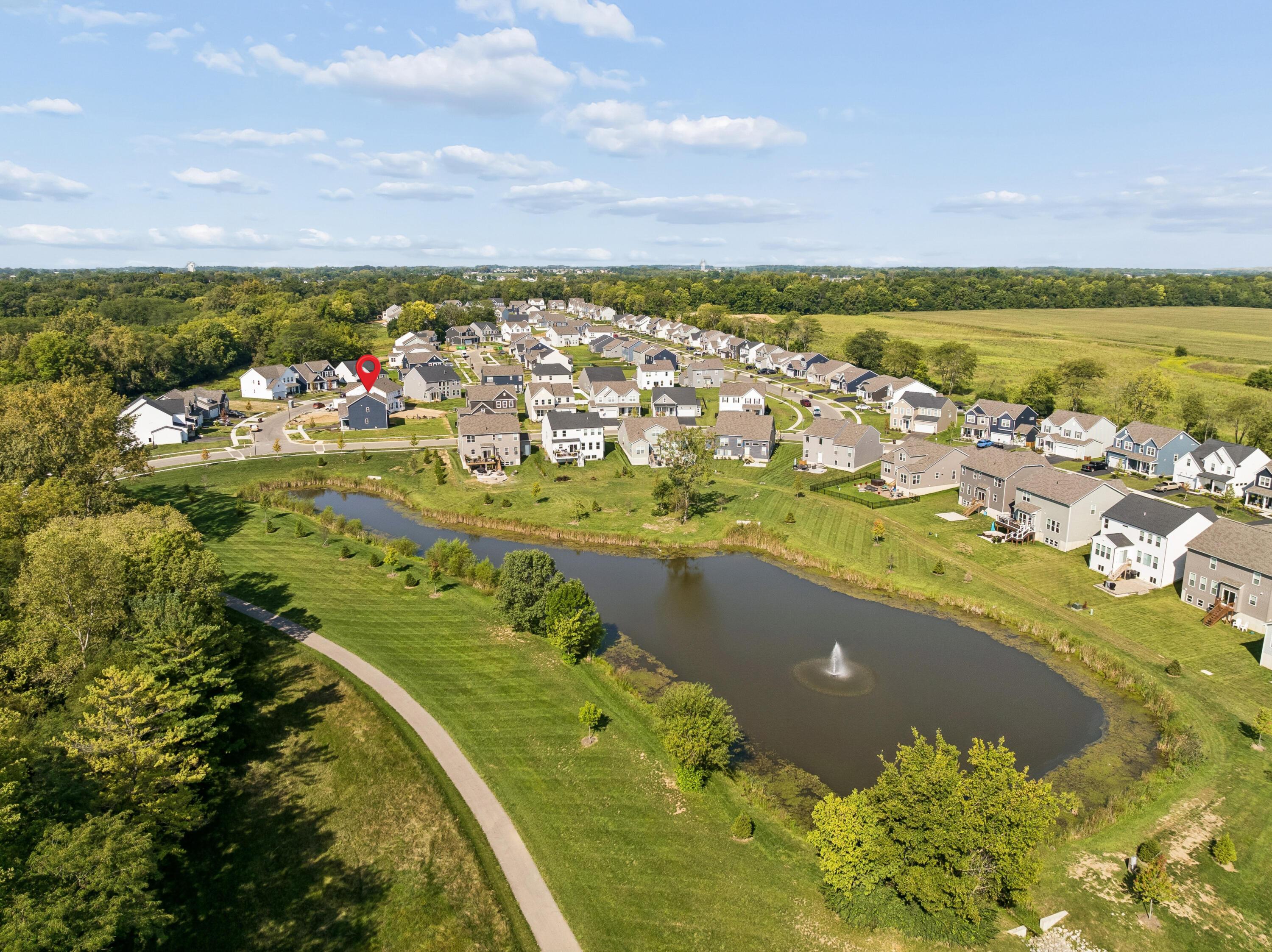 Aerial view of a neighborhood beside a pond, with the featured home marked in red.
