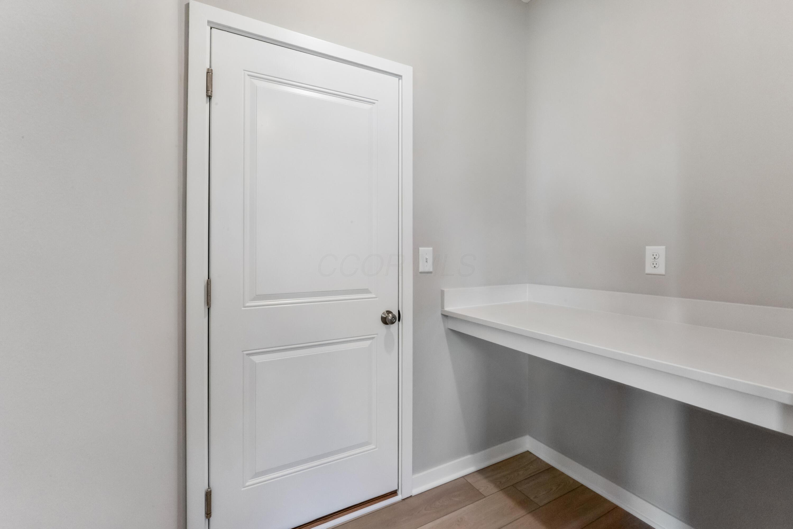 Small room with a white paneled door and a long built-in counter.