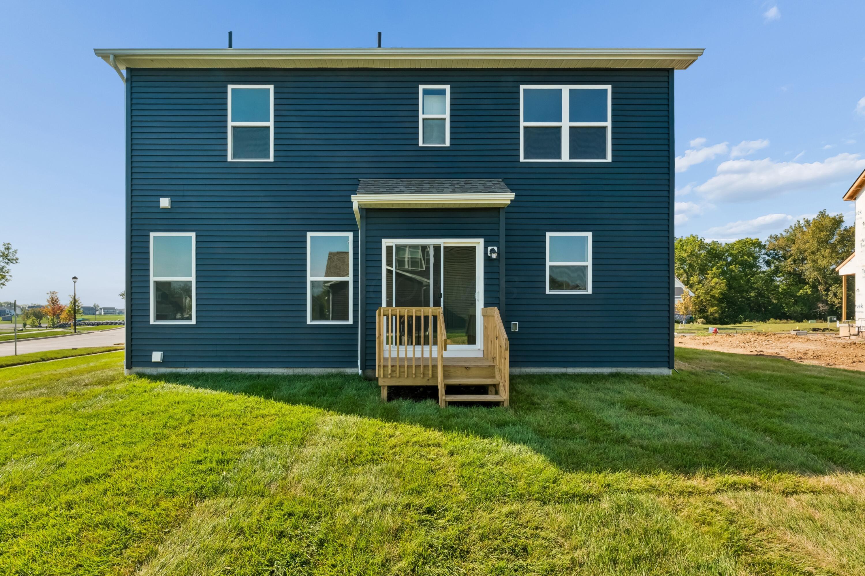 Rear of a dark blue two-story home with white-trimmed windows and a small wooden deck.