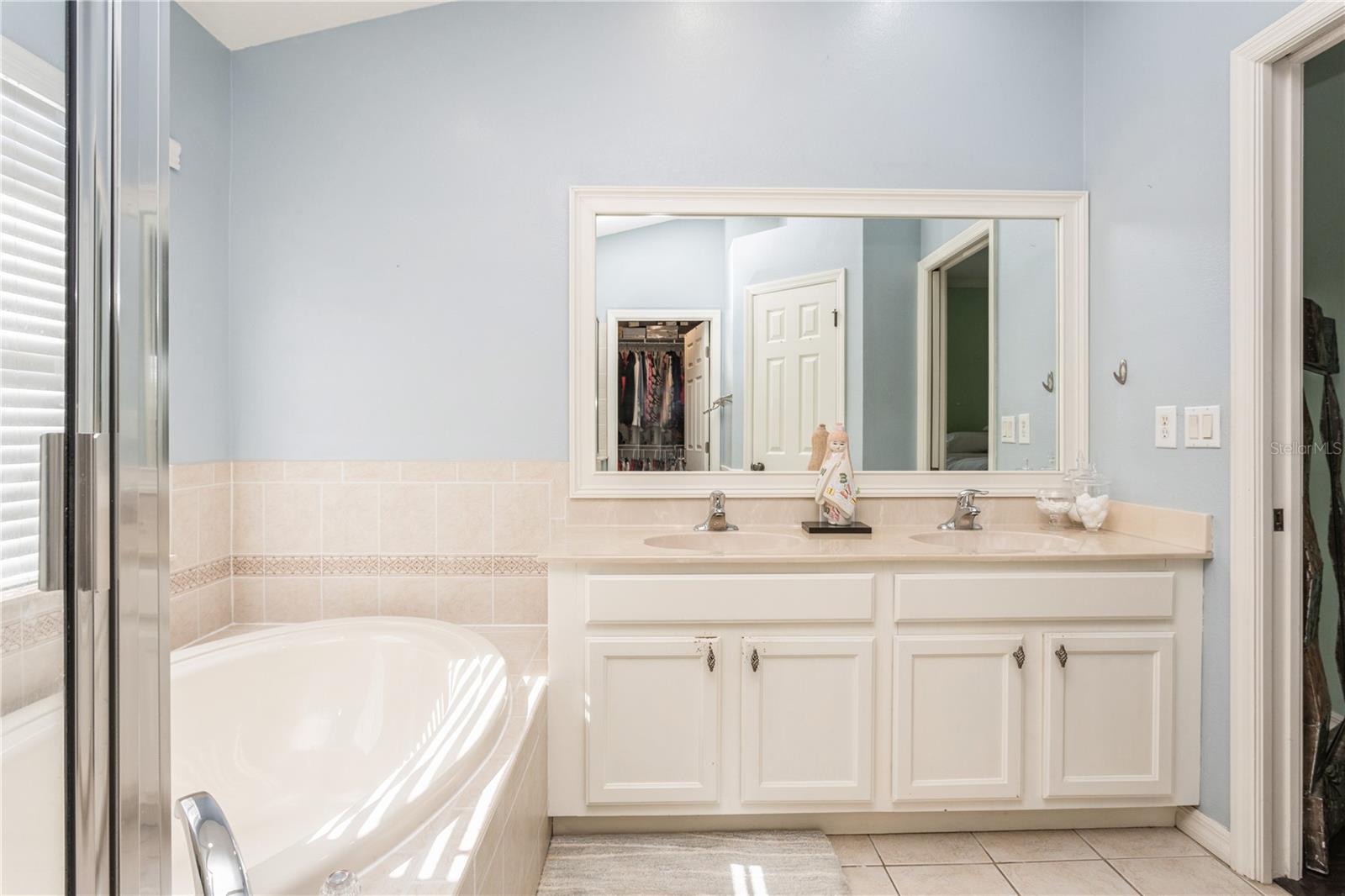 Bathroom with a soaking tub, double-sink vanity, and wide mirror.