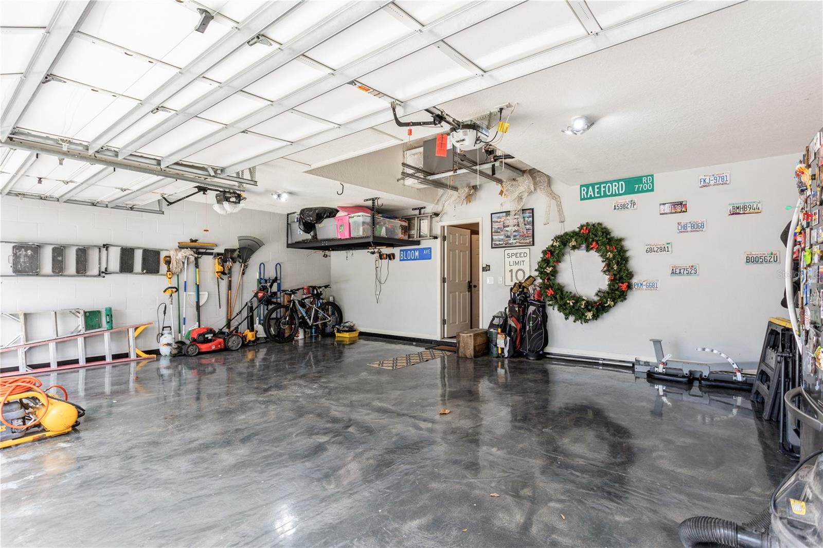 Spacious garage with a polished floor, ceiling storage, bicycles, and street signs and license plates on the wall.