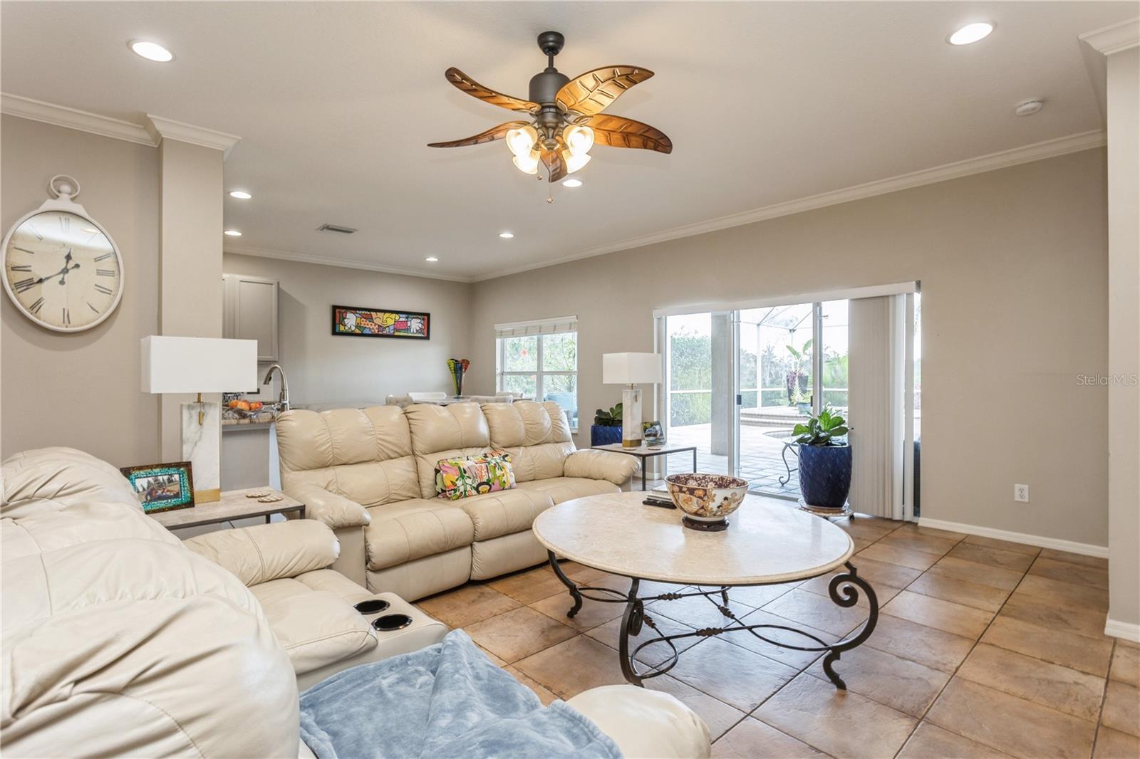 Living room with cream leather sofas, tiled floors, and sliding glass doors to a screened patio.