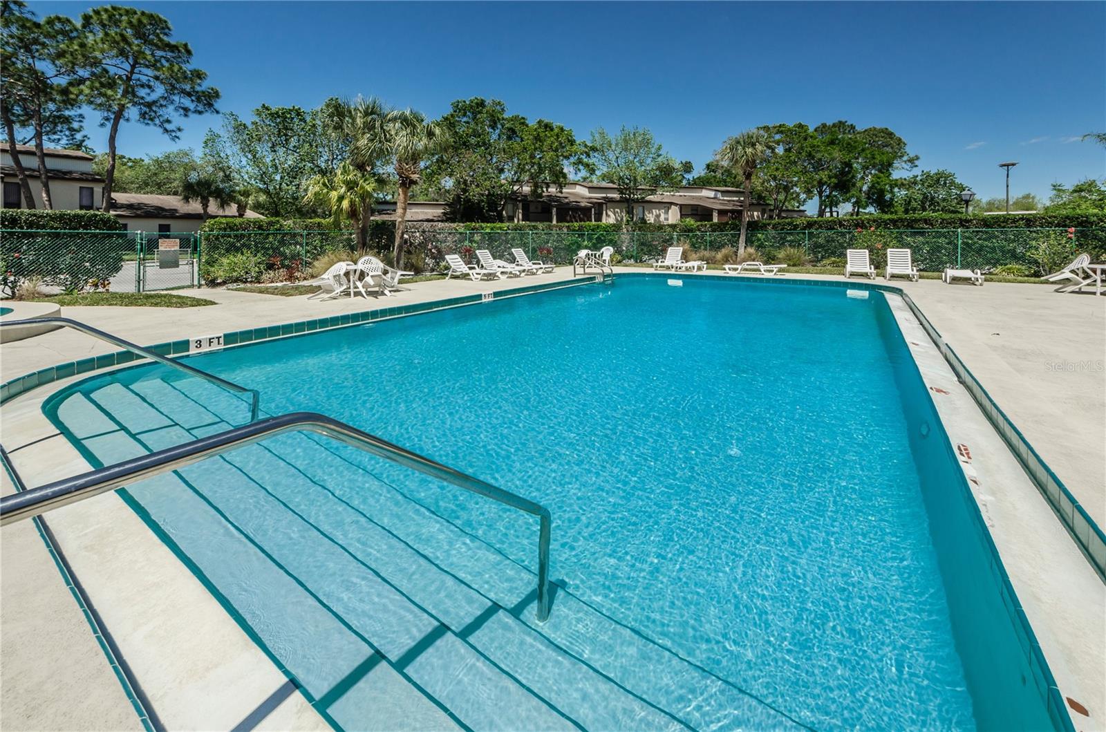 Outdoor swimming pool with broad entry steps and white lounge chairs along the deck.