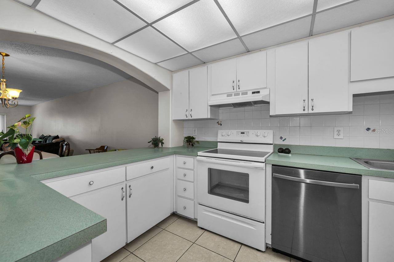 Kitchen with mint-green counters, white cabinetry, and a stainless steel dishwasher.