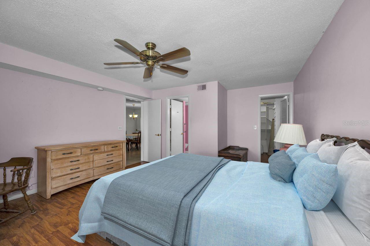 Bedroom with light blue bedding, a wooden dresser, parquet flooring, and a ceiling fan.