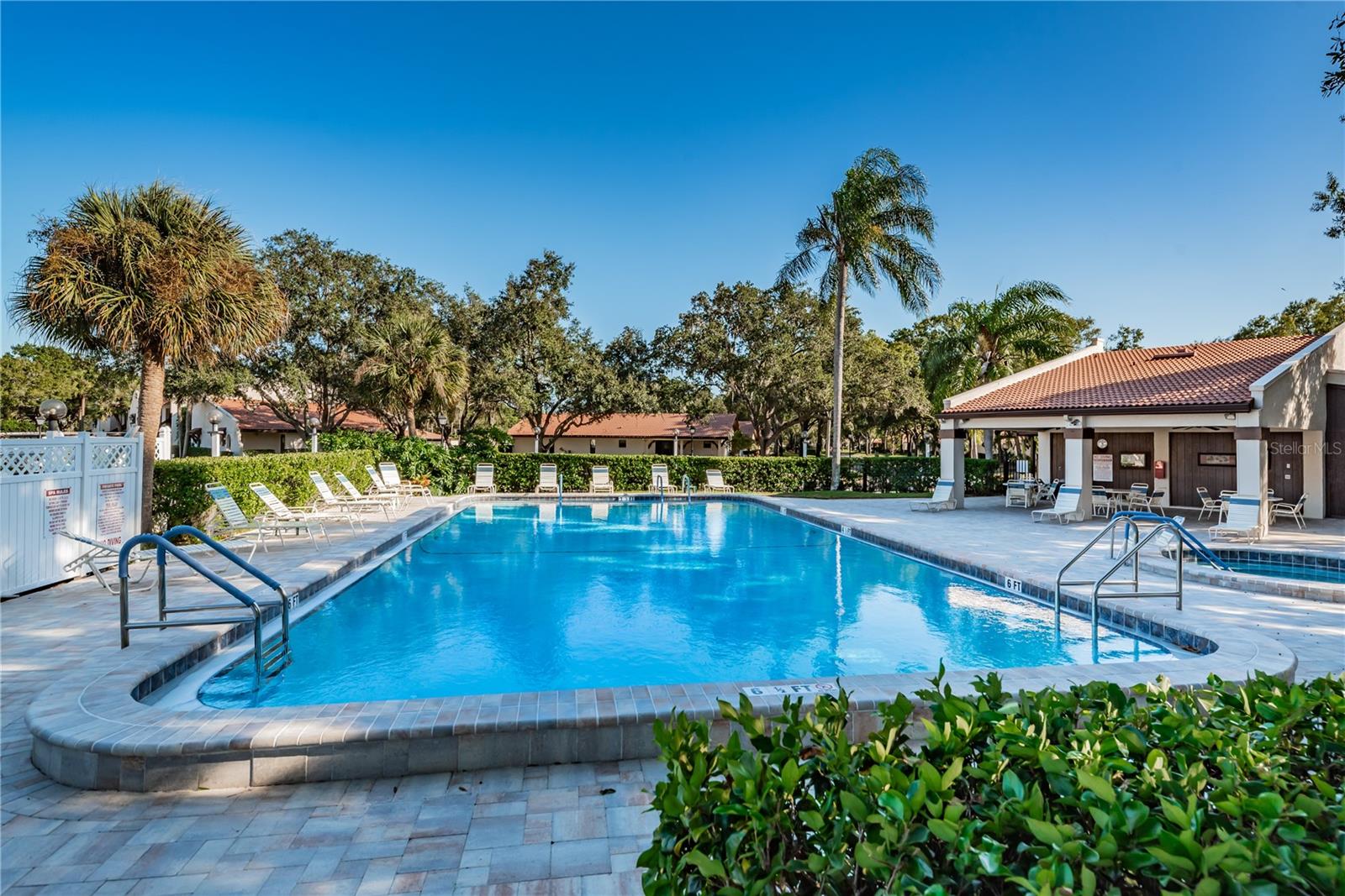 Community pool with lounge chairs, palm trees, and a covered clubhouse area.