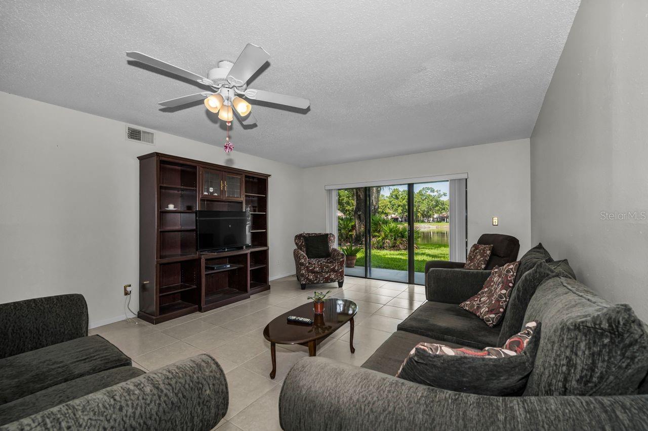 Living room with gray sofas and a pond view through sliding glass doors.