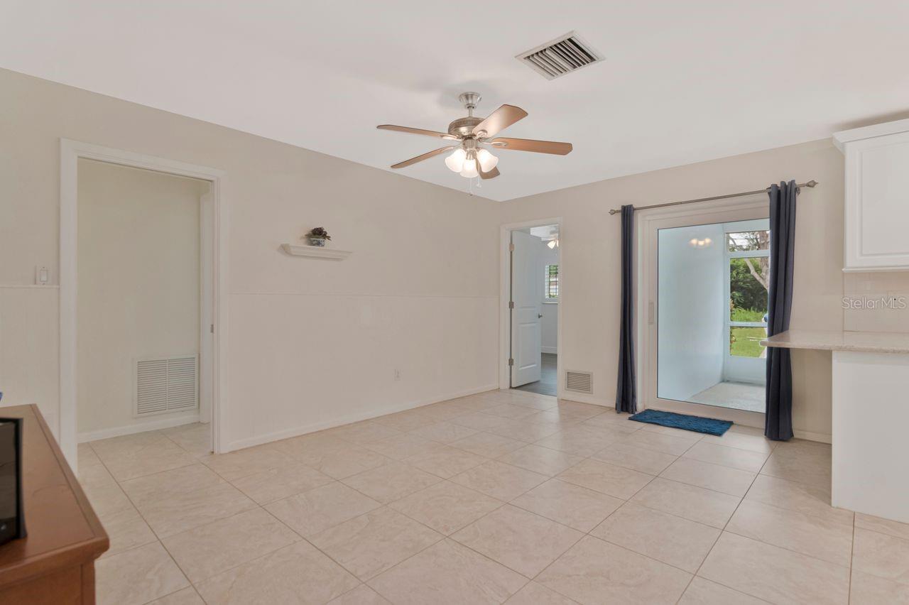 Vacant tiled room with a ceiling fan and sliding glass door to the outdoors.