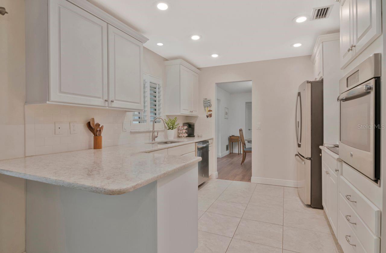 Bright kitchen with white cabinets, a large stone island, and stainless steel appliances.