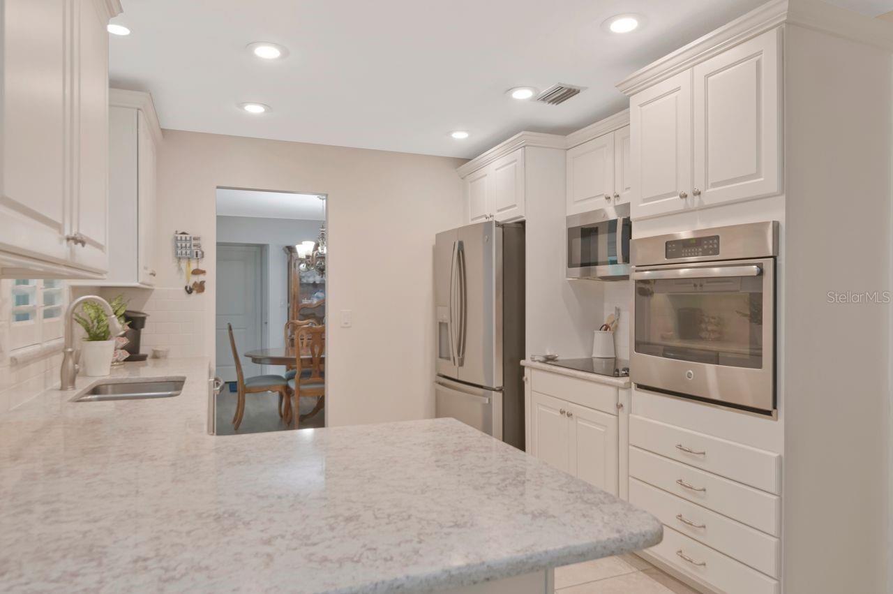 Kitchen with white cabinets, a broad stone island, and stainless steel appliances.