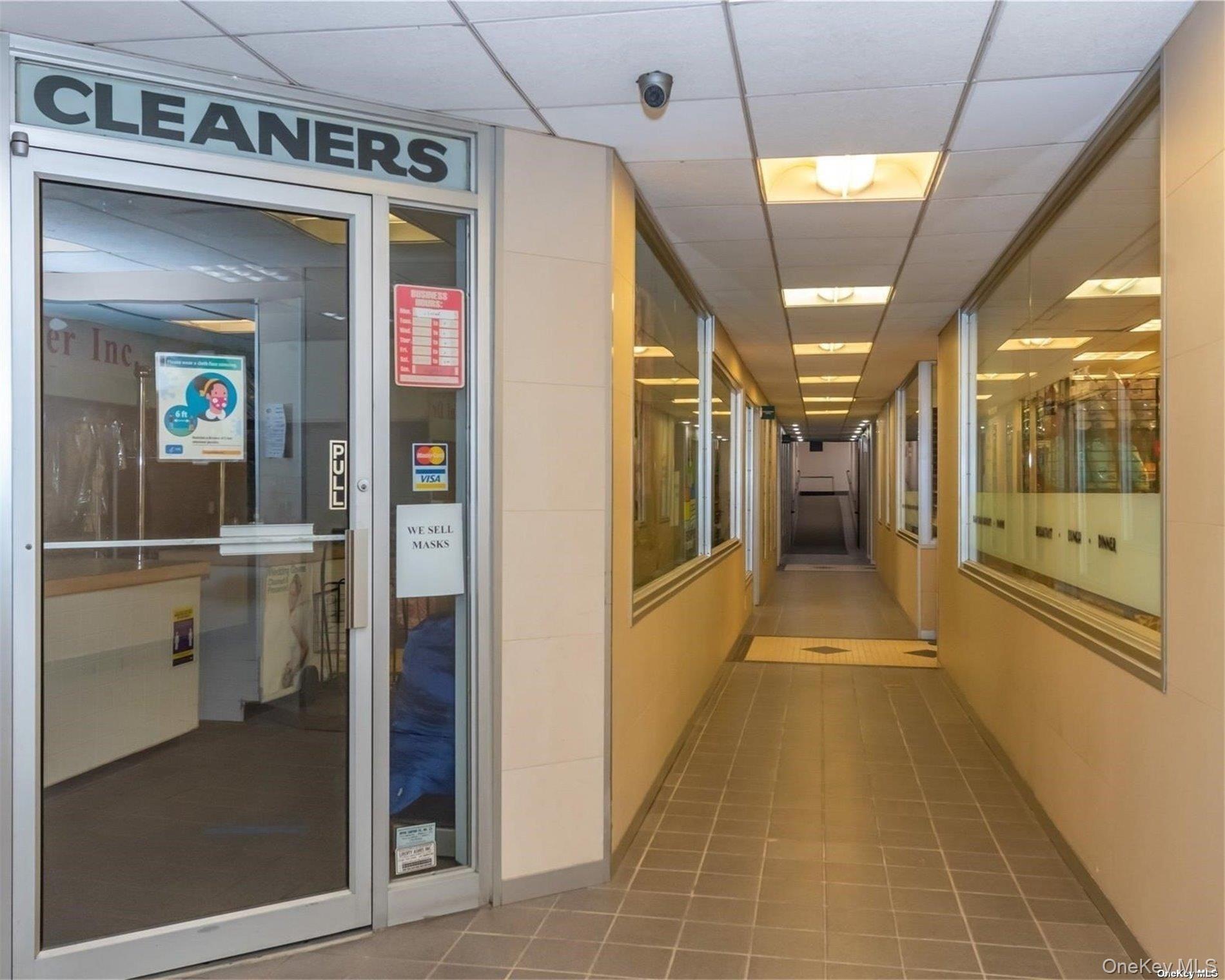 Building hallway with a cleaners storefront and tiled floor.