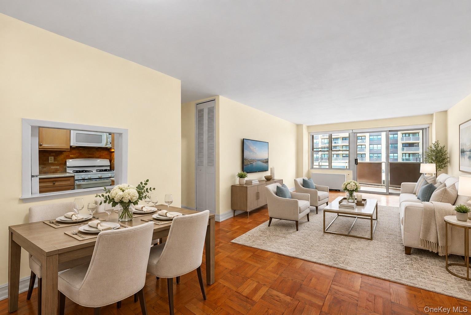 Open-plan living and dining room with parquet floors and a balcony window overlooking nearby buildings.