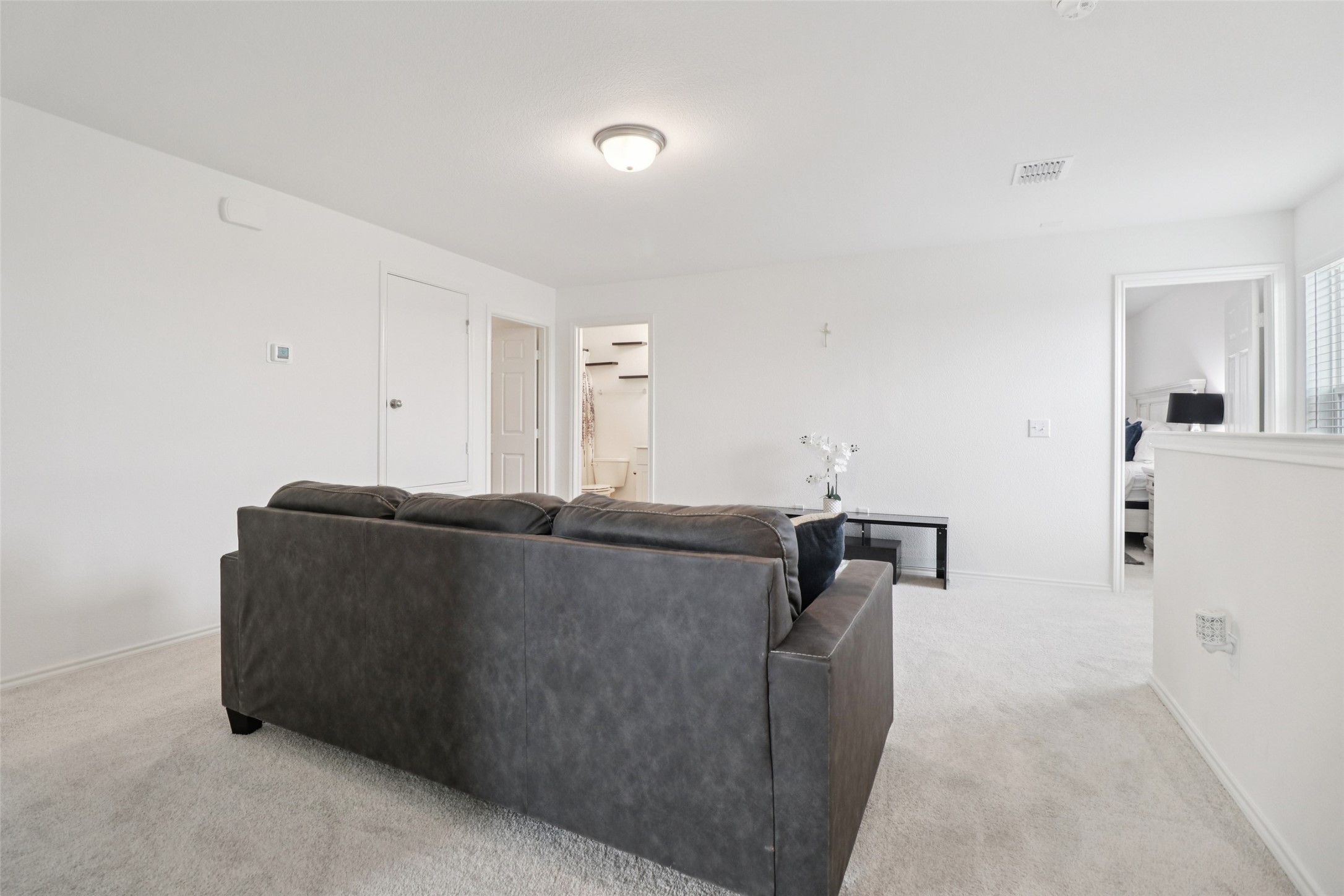 Living room with a dark gray sectional, carpet, and doorways to a bathroom and bedroom.