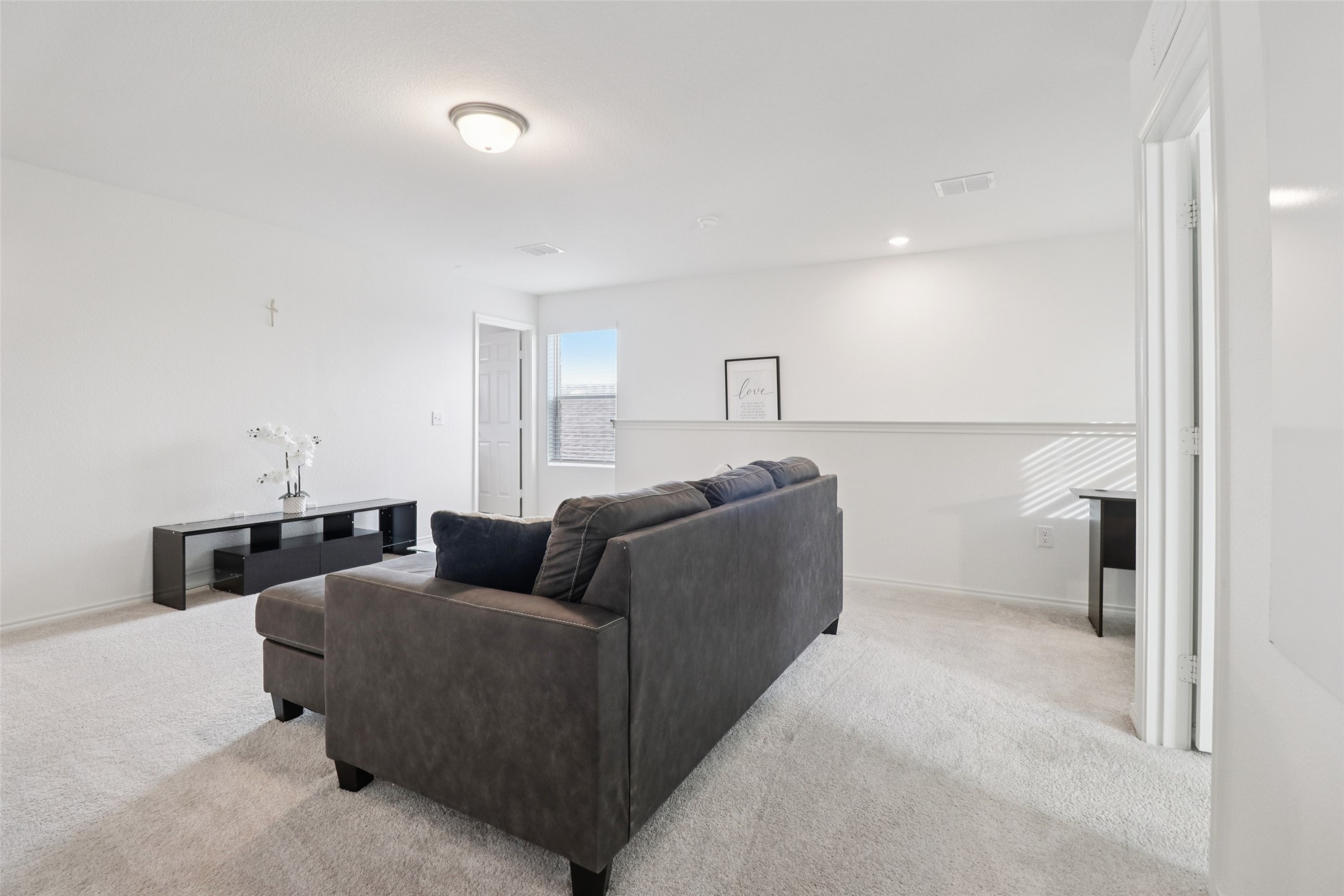 Living room with a dark gray sectional, light carpet, and a half-height wall.