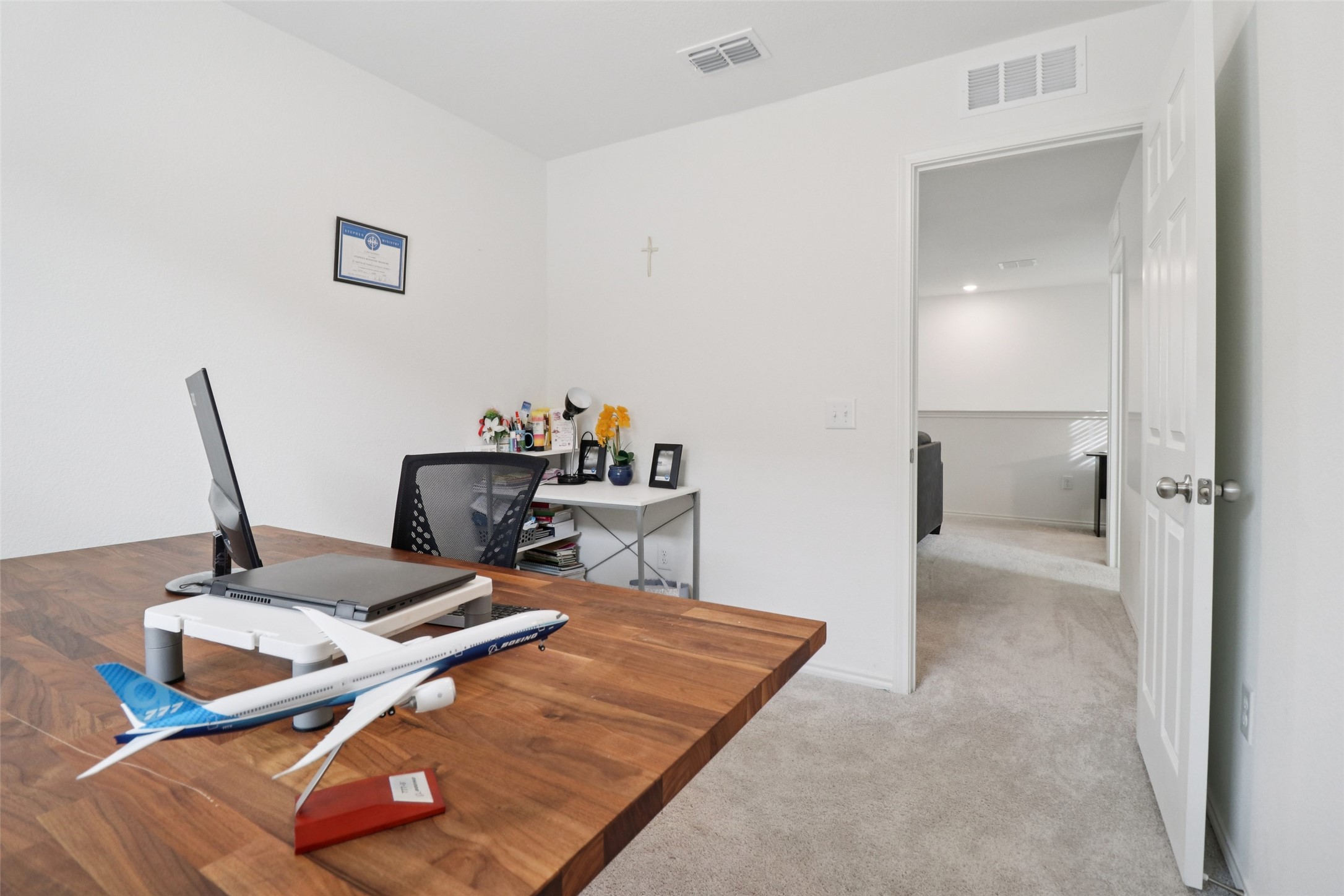 Home office with a large wood desk and a model Boeing airplane.