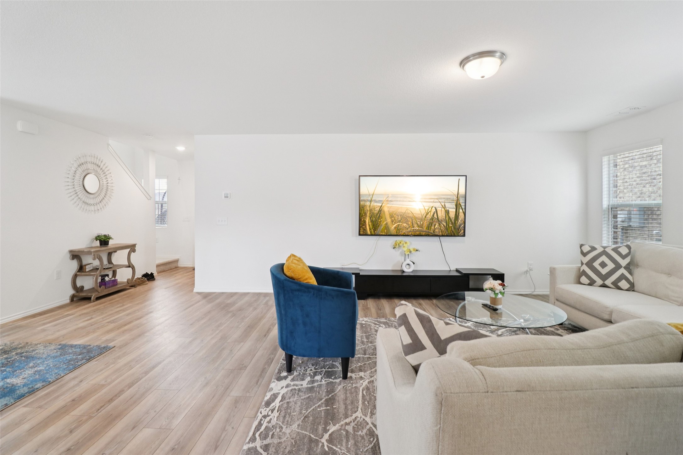 Staged living room with cream sofas, a blue accent chair, and light wood-look floors.