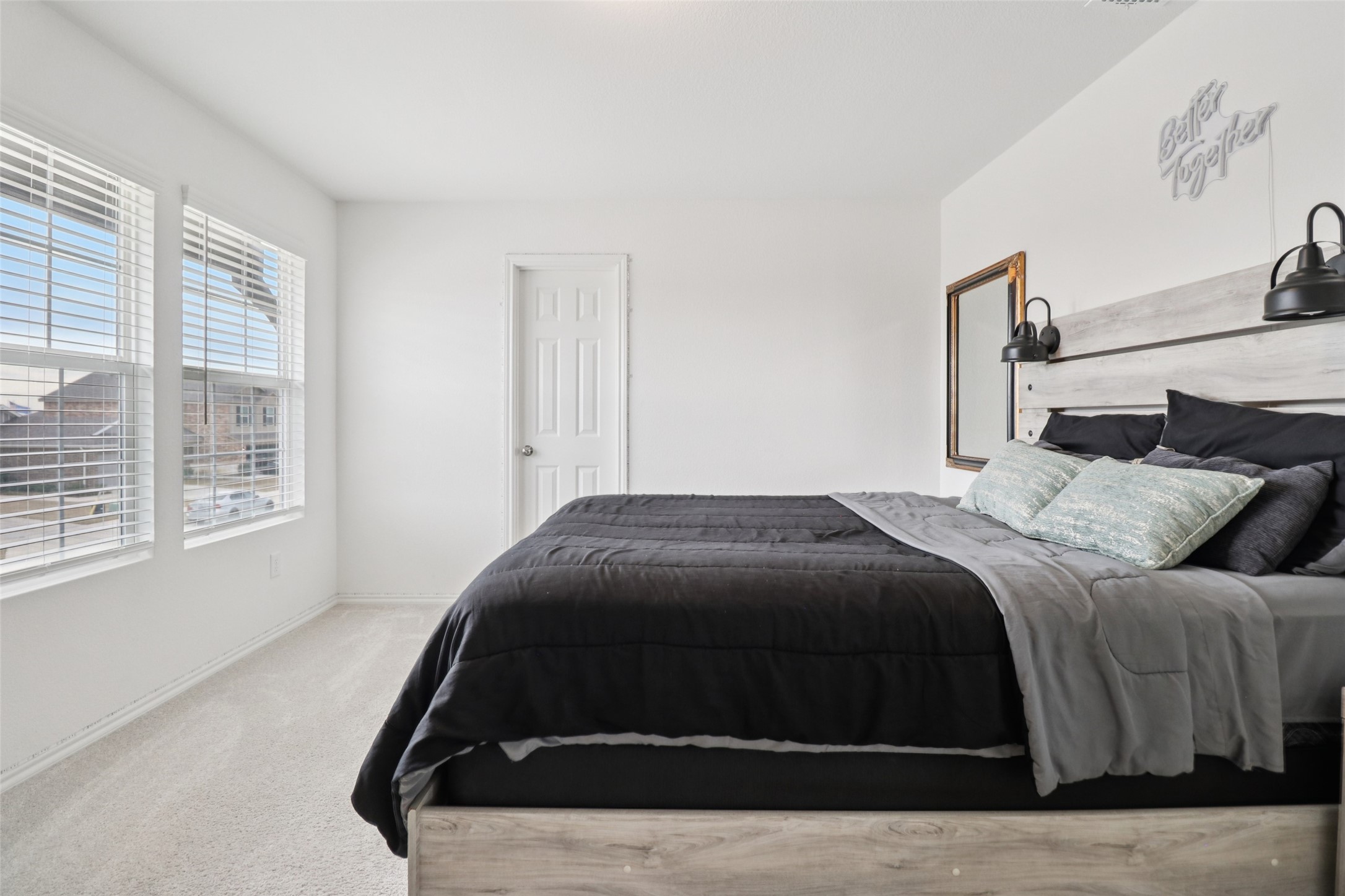 Furnished bedroom with a charcoal bed, pale wood headboard, and two bright windows.