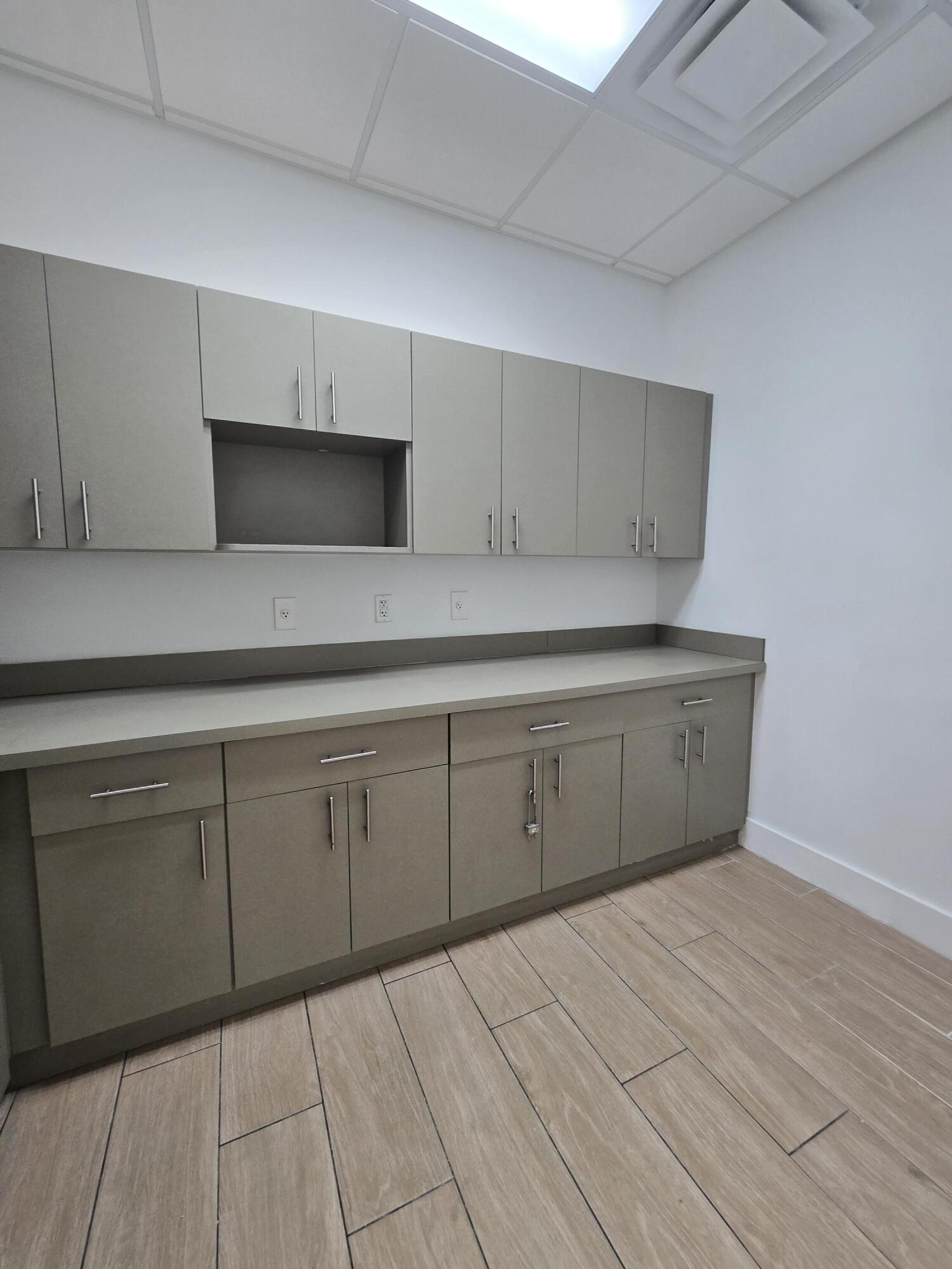 Empty interior with gray built-in cabinets and countertop beneath a bright ceiling skylight.